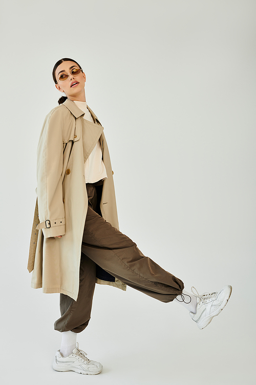 In a modern studio, a young woman strikes a pose, flaunting her trendy autumn outfit with confidence and style.