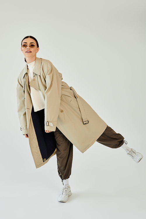 A young woman elegantly poses in a chic autumn ensemble, bringing a touch of fashion to the studio backdrop.