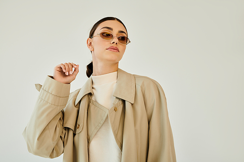 A young woman poses elegantly, highlighting her stylish autumn outfit in a contemporary studio setting, radiating confidence.