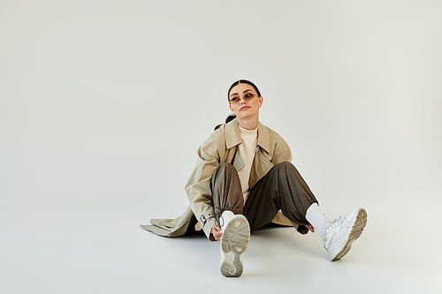 Embracing the autumn vibe, a young woman poses elegantly in a trendy outfit, radiating confidence in a modern studio.