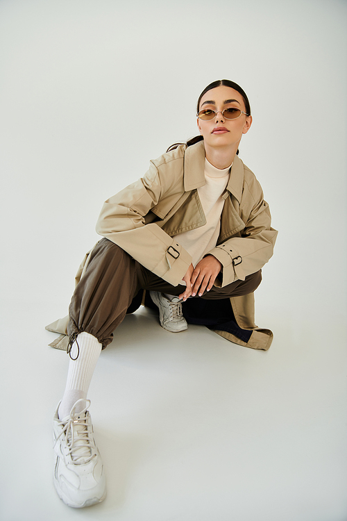 A young woman poses confidently in a chic autumn outfit, blending elegance with modern style in a studio.