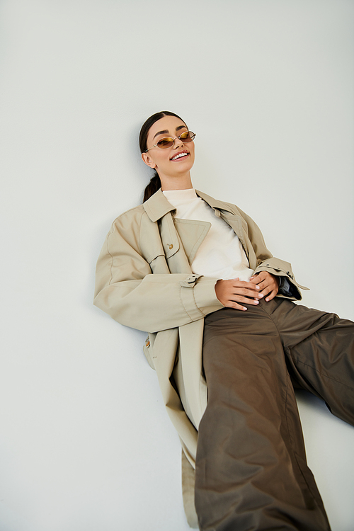 A young woman exudes confidence in a chic autumn outfit, posing gracefully in a stylish studio space.