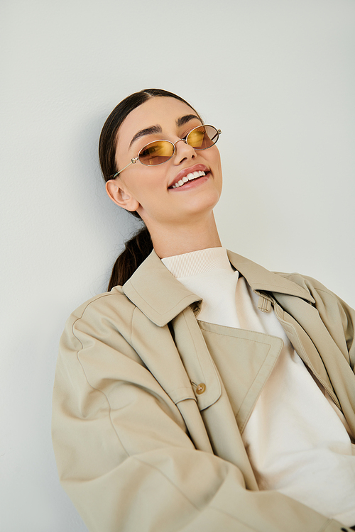 A chic and confident young woman showcases her stylish autumn attire in a trendy studio setting, embodying seasonal fashion.