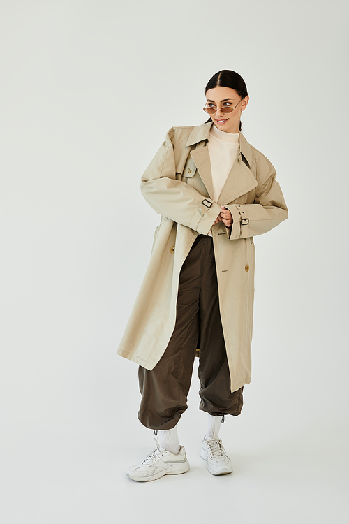 A young woman poses confidently in a chic autumn ensemble, radiating style and elegance in a studio backdrop.