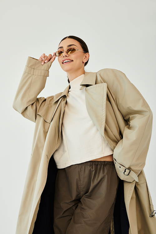 A young woman models a chic autumn outfit, exuding confidence and style in a bright studio setting.