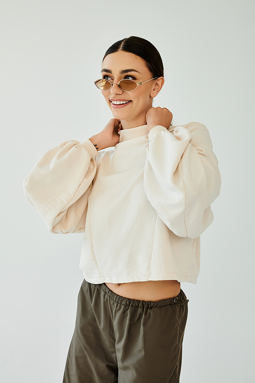 A young woman radiates confidence, posing gracefully in her fashionable autumn attire within a warm studio environment.