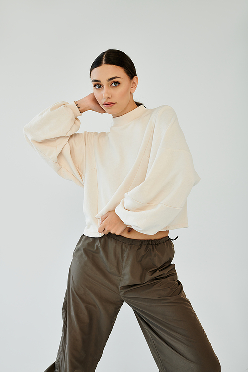 A fashionable young woman showcases her stylish autumn ensemble, exuding elegance in a modern studio environment.