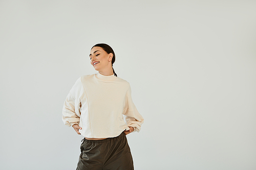 A young woman radiates confidence in a stylish autumn outfit, playfully posing in a modern studio backdrop.