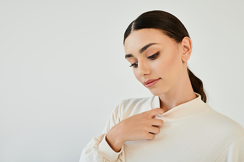 A graceful young woman models a fashionable autumn outfit, exuding elegance in a minimalist studio backdrop.