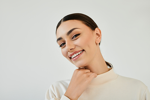 A young woman radiates beauty and confidence, showcasing a chic autumnal outfit in a serene studio setting.