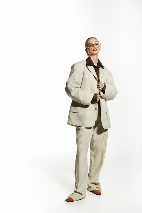 A stylish young woman stands confidently in a cream suit, her eyes looking directly at the camera.