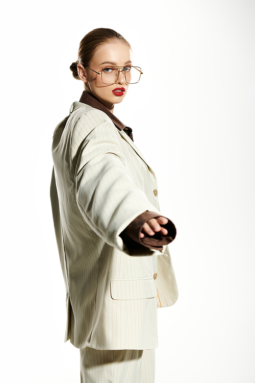 A young woman with red lips and glasses poses confidently in a white suit.