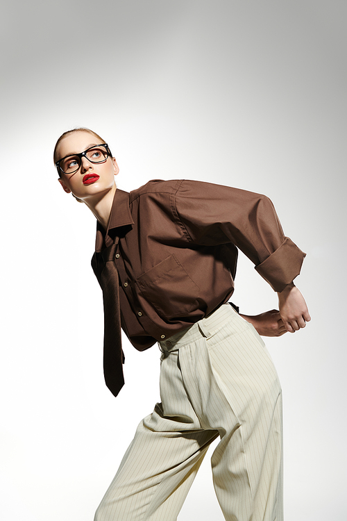 A young woman in a brown shirt and white pants poses against a white background.