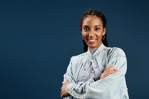 A confident young woman shows off her stylish outfit against a bright blue backdrop.