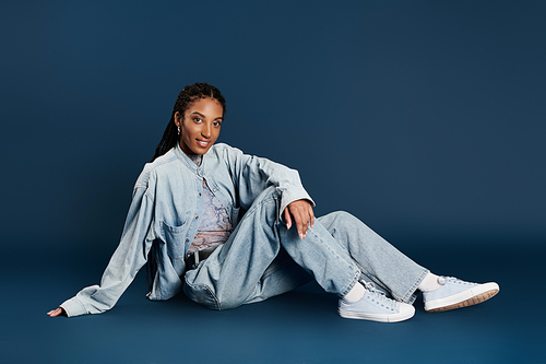 The young woman showcases her fashionable outfit while relaxing on the floor, exuding confidence.