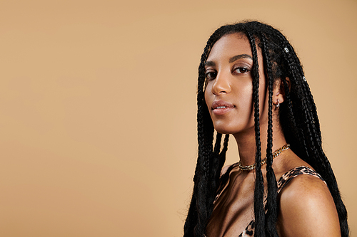 A fashionable young woman showcases her unique style with long braids and elegant attire.