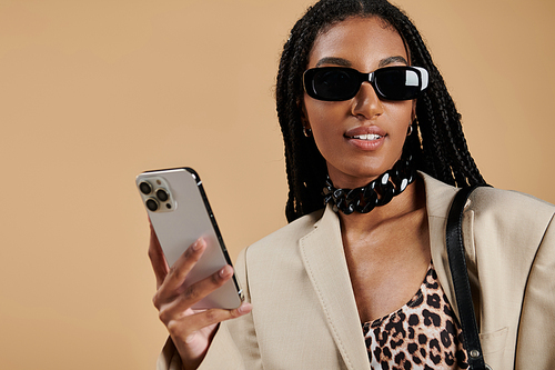 A stylish young woman flaunts her trendy outfit and smartphone, radiating confidence.