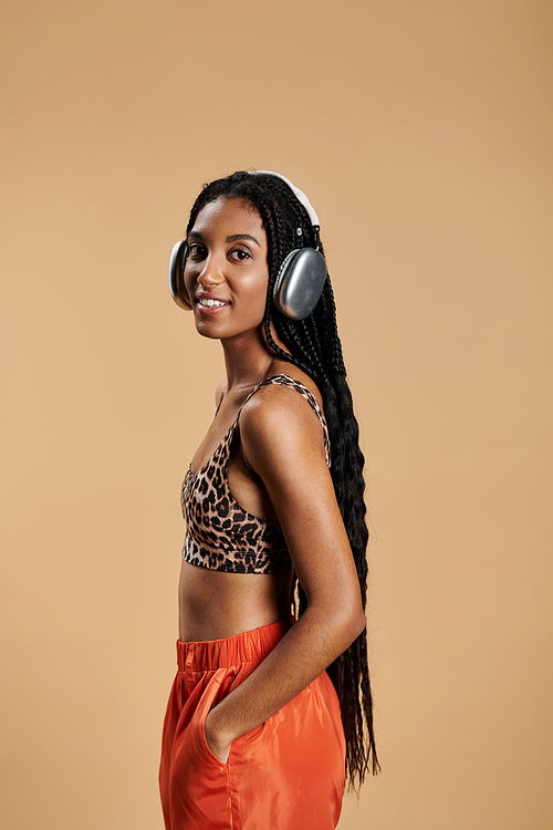 A beautiful young woman with long braids showcases her trendy outfit while listening to music.