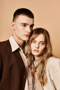 attractive young woman in stylish suit posing with her handsome boyfriend and looking at camera