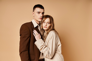 attractive young woman in stylish suit posing with her handsome boyfriend and looking at camera