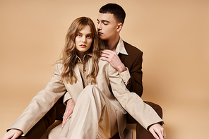 beautiful woman in chic suit posing next to her good looking loving boyfriend and looking at camera