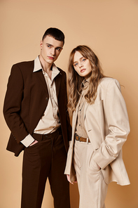 elegant young woman in stylish suit posing with her handsome boyfriend and looking at camera