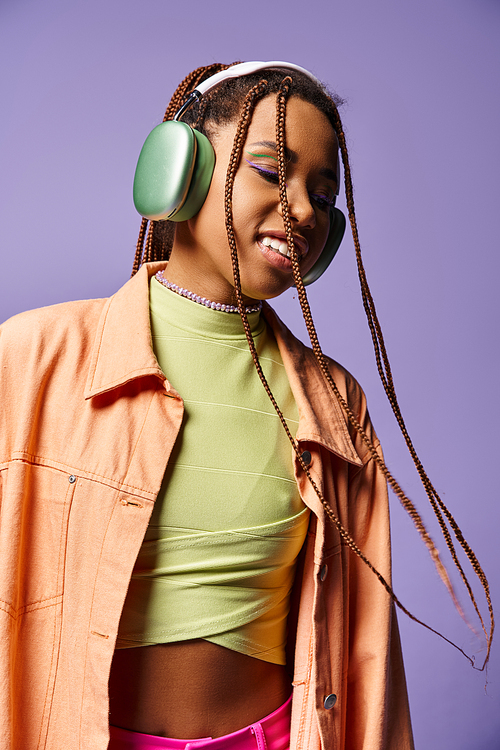 jolly african american girl in 20s listening music in wireless headphones, moving to rhythm, dance