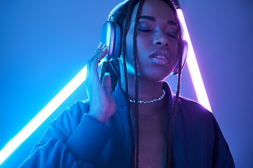 charming african american woman in headphones enjoying music in studio with fluorescent light