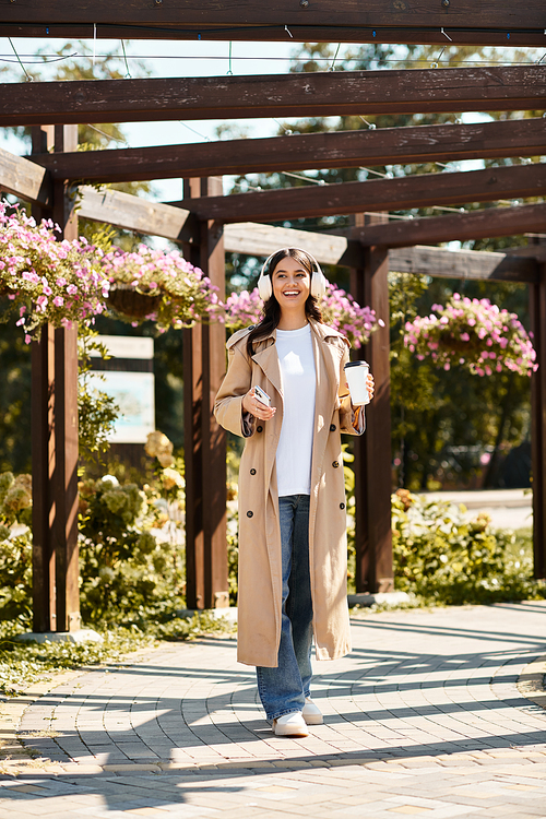 A young woman relaxes in a sunny park, dressed stylishly and sipping a warm drink.