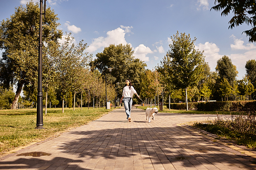 A young woman enjoys a leisurely walk in the park, dressed warmly for the beautiful autumn day.