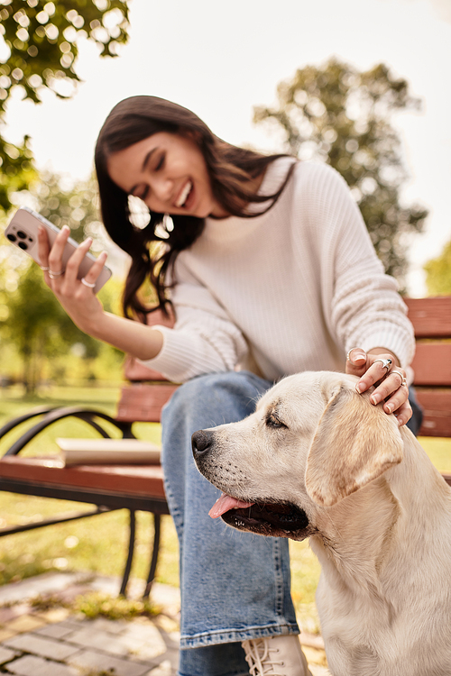 A joyful woman in cozy autumn attire smiles at her dog while relaxing in the park.