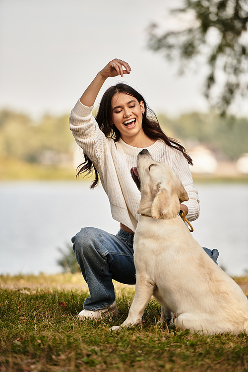 A young woman laughs as she engages with her golden retriever, enjoying a beautiful autumn day.