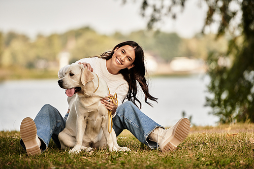 A young woman dressed warmly plays with her dog, surrounded by autumns golden hues.