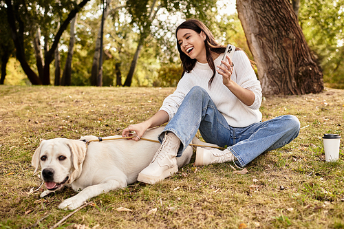 A joyful woman in warm attire shares a light moment with her dog on a lovely autumn afternoon.