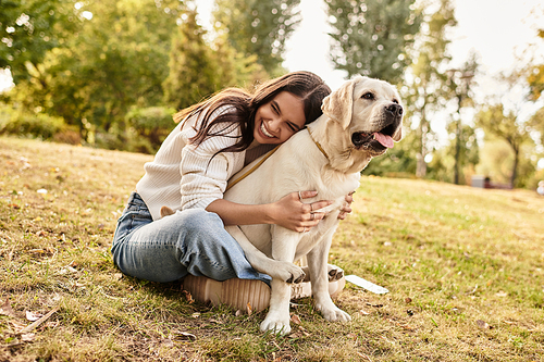 In a vibrant park setting, a young woman in autumn attire shares a joyful moment with her dog.