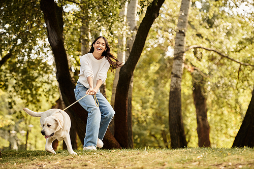 A joyful young woman in cozy autumn attire plays with her dog amidst fall colors.