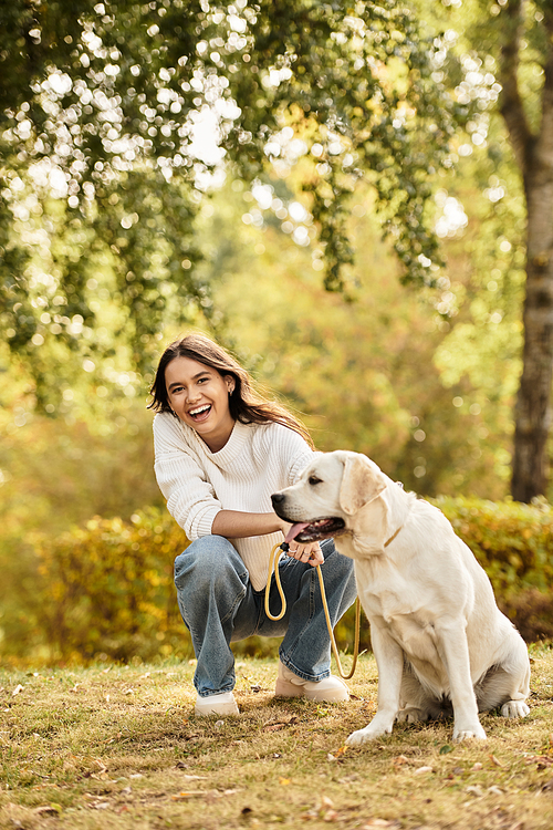 A young woman enjoys a vibrant autumn afternoon, smiling with her dog in the park.