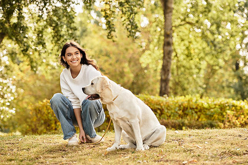 The woman in warm autumn attire smiles while spending joyful moments outdoors with her dog.