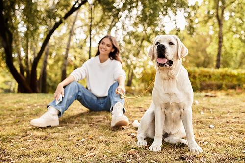 A beautiful woman dressed for autumn relaxes in a park with her playful dog by her side.