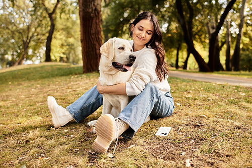 A young woman embraces her loyal dog while sitting on the grass in a serene autumn park.