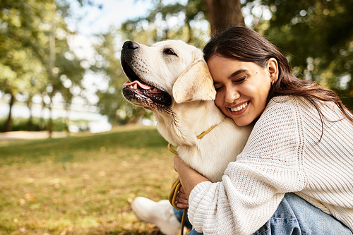 In the park, a young woman enjoys a heartwarming moment with her dog amidst autumn leaves.