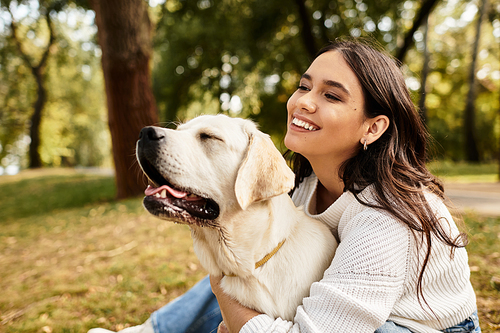 A young woman embraces her dog warmly, enjoying a peaceful autumn day in the park.