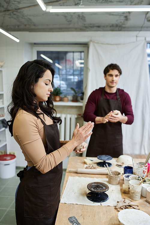 A couple joyfully molds clay, sharing creativity in a contemporary pottery studio.