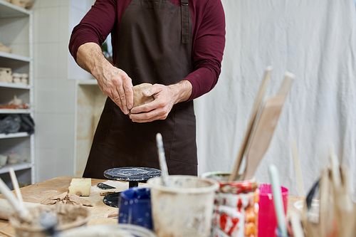 Sophisticated dedicated man in apron making some pottery in studio.