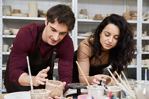 A couple joyfully shapes clay in a contemporary pottery studio.