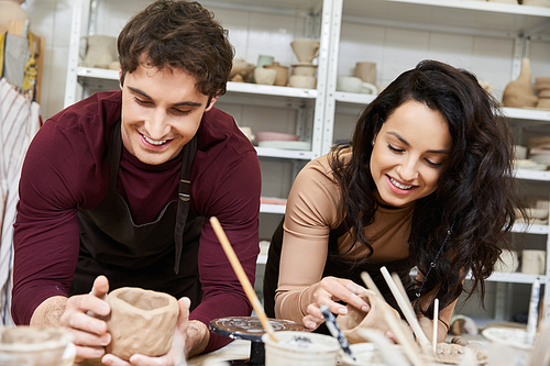 A loving couple shapes clay, sharing smiles and creativity in their pottery studio.