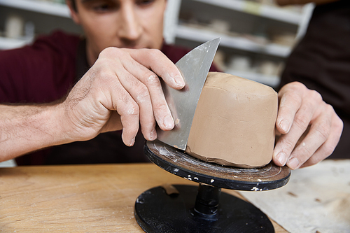 Sophisticated hard working man in apron making some pottery in studio.