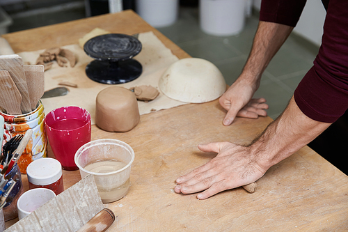 Elegant hard working man in apron making some pottery in studio.