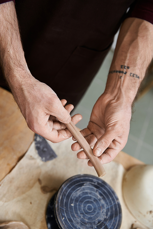 Devoted stylish man in apron making some pottery in studio.