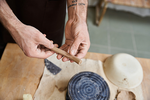 Devoted trendy man in apron making some pottery in studio.